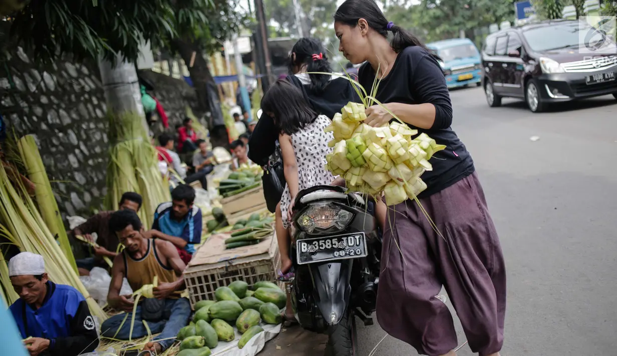 Seorang wanita usai membeli kulit ketupat di Pasar Palmerah, Jakarta, Senin (2/6/2019). Peningkatan drastis dikarenakan banyak warga yang ingin membuat masakan khas Lebaran seperti Opor Ayam yang selalu ditemani ketupat sebagai pengganti lontong. (Liputan6.com/Faizal Fanai)