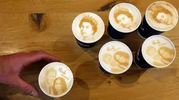 Seorang pria memegang kopi Capuccino dengan dengan latte art gambar Pangeran Harry dan Meghan Markle di kedai kopi, Windsor, 15 Mei 2018. Inggris sedang mempersiapkan pernikahan Harry dan Meghan pada 19 Mei mendatang di Windsor Castle. (AP/Frank Augstein)