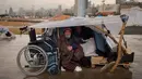 Situasi ini imbas eskalasi serangan udara Israel yang meluas di wilayah selatan, dan pinggiran Beirut, Lebanon. Tampak dalam foto, seorang pria bersama istrinya, yang mengungsi dari pinggiran selatan Beirut, Dahiyeh, berlindung dari hujan di dalam tenda di sepanjang pantai, Beirut, Lebanon, Kamis, 26 Maret 2026. (AP Photo/Emilio Morenatti)