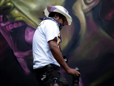 Seorang seniman yang bernama Montalvo Tekuene melewati salah satu karya grafiti dalam festival pekan grafiti di Mexico City, Meksiko, Minggu (9/10). Grafiti merupakan salah satu seni jalanan yang populer hingga kini. (REUTERS/Carlos JASSO)