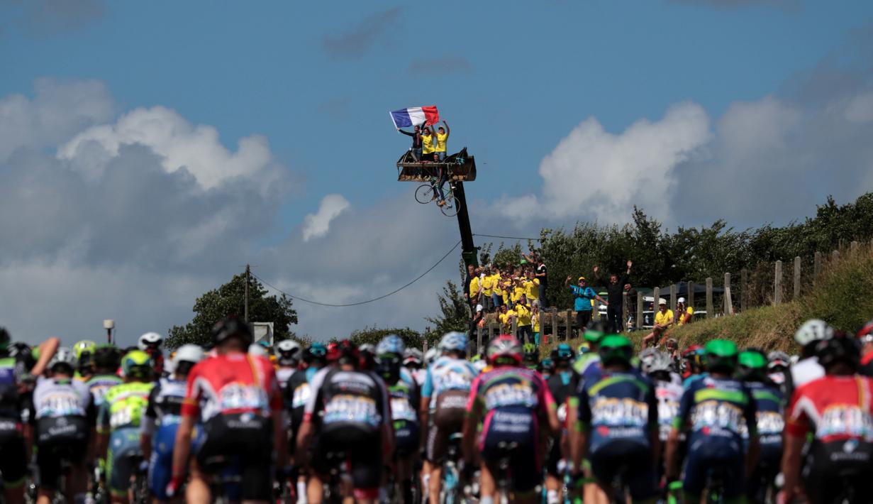 Penonton naik di atas crane saat menyambut pebalap yang berlomba di Etape1 Tour de France antara Mont-Saint-Michel dan Utah Beach Sainte-Marie-du-Mont, Normandy, (2/7/2016). (AFP/Kenzo Tribouillard)