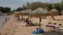 Panel surya terpasang pada sejumlah payung di pantai dekat Balai Kota Vari-Voula-Vouliagmeni, Yunani, Selasa (21/7/2020). Puluhan payung di sepanjang pantai tersebut dilengkapi sistem panel surya dan port USB untuk menyediakan pengisian daya gratis dan ramah lingkungan. (Xinhua/Lefteris Partsalis)