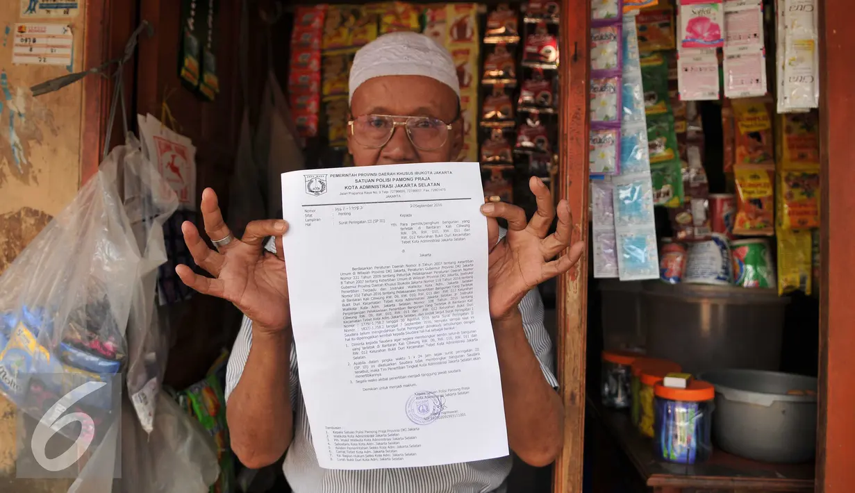 Warga menunjukan surat peringatan ke 3 di Kawasan Bukit Duri, Jakarta, Selasa (20/9). Pemkot Jaksel akan menertibkan bangunan dan permukiman di kawasan Bukit Duri yang berbatasan langsung dengan Sungai Ciliwung. (Liputan6.com/Gempur M Surya)