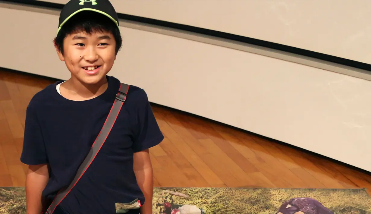 Seorang anak berpose dengan gambar 3D monster pada pameran seni trik 3D karya seniman Jepang Masashi Hattori di Kawasaki, dekat Tokyo, Sabtu, (5/8). (AP Photo / Koji Sasahara)