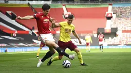 Pemain Manchester United Harry Maguire (kiri) berebut bola dengan pemain Burnley Johann Berg Gudmundsson pada pertandingan Liga Inggris di Stadion Old Trafford, Manchester, Inggris, Minggu (18/4/2021). Manchester United menang 3-1. (Gareth Copley/Pool via AP)