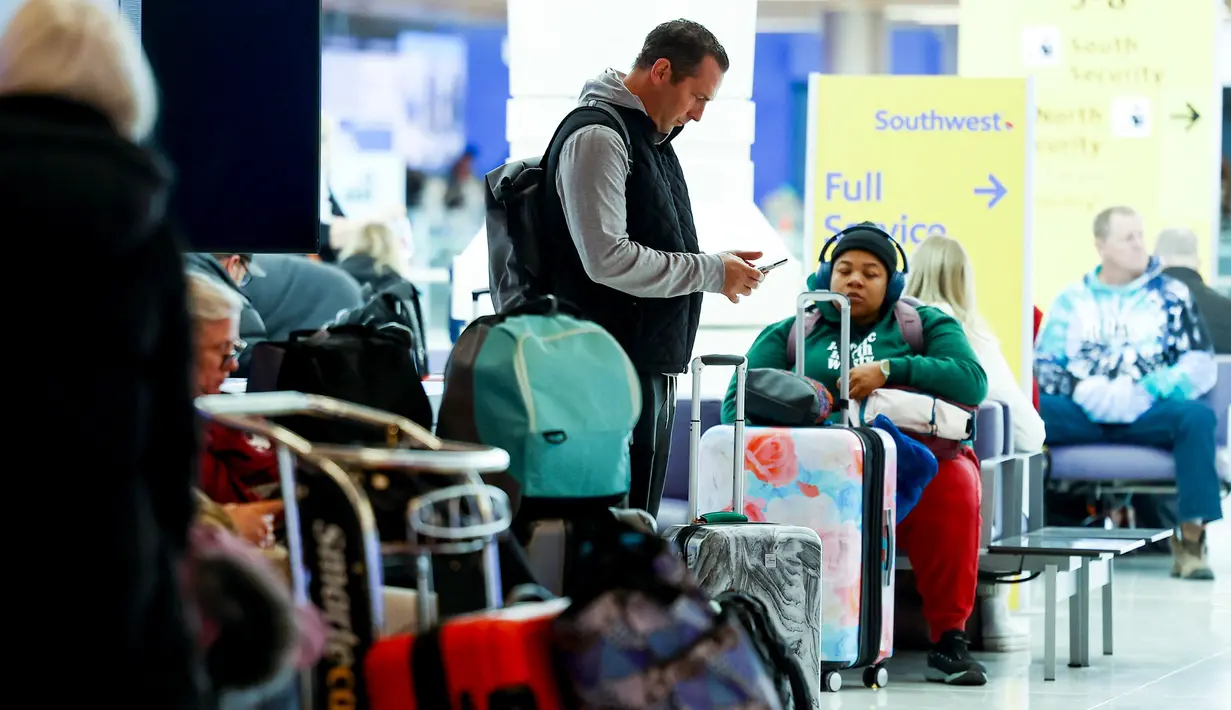 Seorang pelancong memeriksa ponselnya selama badai musim dingin di Bandara Internasional Denver di Denver, Colorado, Rabu (22/2/2023). Lebih dari 1.000 penerbangan telah dibatalkan di seluruh Amerika Serikat (AS) karena badai berdampak pada perjalanan di seluruh negeri. (Michael Ciaglo/Getty Images/AFP)