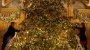 Dekorator menghias pohon cemara besar dari Windsor Great Park di ujung aula St. George di Windsor Castle, Inggris, 30 November 2018. Pohon setinggi 6 meter itu dihias dengan pernak-pernik Natal berwarna emas serta ornamen kerajaan.  (AP/Frank Augstein)