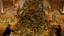 Dekorator menghias pohon cemara besar dari Windsor Great Park di ujung aula St. George di Windsor Castle, Inggris, 30 November 2018. Pohon setinggi 6 meter itu dihias dengan pernak-pernik Natal berwarna emas serta ornamen kerajaan.  (AP/Frank Augstein)