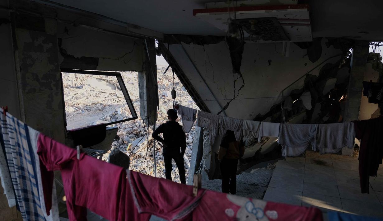 Secara umum, sekitar 80 persen wilayah utara Gaza telah hancur akibat serangan Israel. Tampak dalam foto, anak-anak berdiri di dalam sebuah gedung apartemen yang rusak parah di Jabalia, di bagian utara Jalur Gaza, meskipun kerusakan yang parah, pada Minggu 7 Desember 2025. (AP Photo/Jehad Alshrafi)