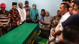 Orangtua (tengah dan kanan) bersama anggota keluarga berkumpul dekat peti mati  jenazah korban jatuhnya pesawat Lion Air JT 610 Jannatun Cintya Dewi sebelum pemakaman di kediaman kawasan Sukodono, Sidoarjo, Jawa Timur, Kamis (1/11). (JUNI KRISWANTO / AFP)