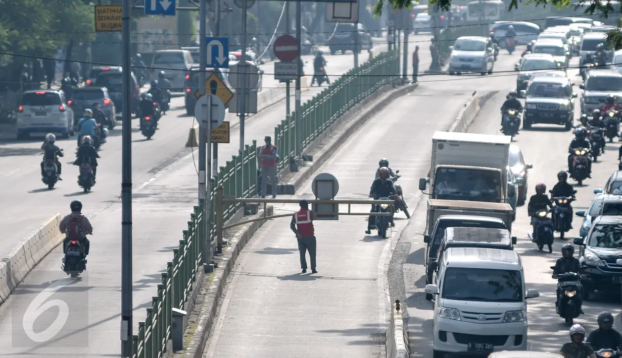 Tampak petugas menjaga palang lintasan Busway di Jalan Sultan Agung, Manggarai, Jakarta, Kamis (28/7). Meski dijaga petugas, sejumlah pengendara motor tetap nekat masuk jalur bus TransJakarta. (Liputan6.com/Yoppy Renato)