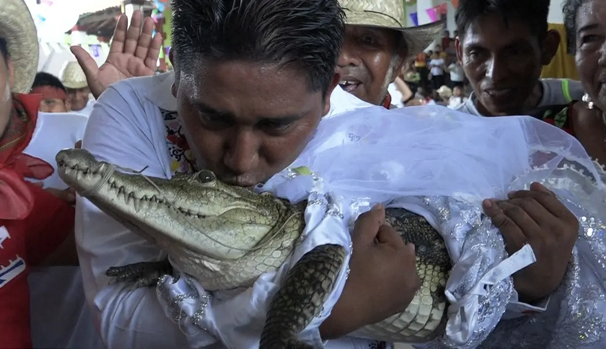 <p>Wali Kota San Pedro Huamelula, Victor Hugo Sosa mencium buaya bernama "La Ni&ntilde;a Princesa" (Gadis Putri) sebelum menikahinya di San Pedro Huamelula, Negara Bagian Oaxaca, Meksiko, Jumat (30/6/2023). (RUSVEL RASGADO/AFP)</p>