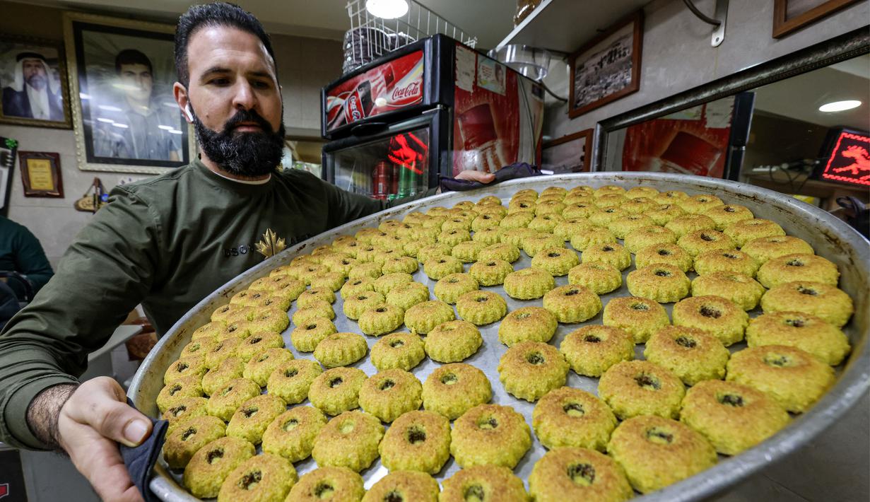 Kudapan manis itu berbentuk bulat, diisi dengan kurma atau kenari, pistachio dan kacang-kacangan. Lapisan luarnya ditaburi gula putih halus. (Photo by AHMAD GHARABLI / AFP)