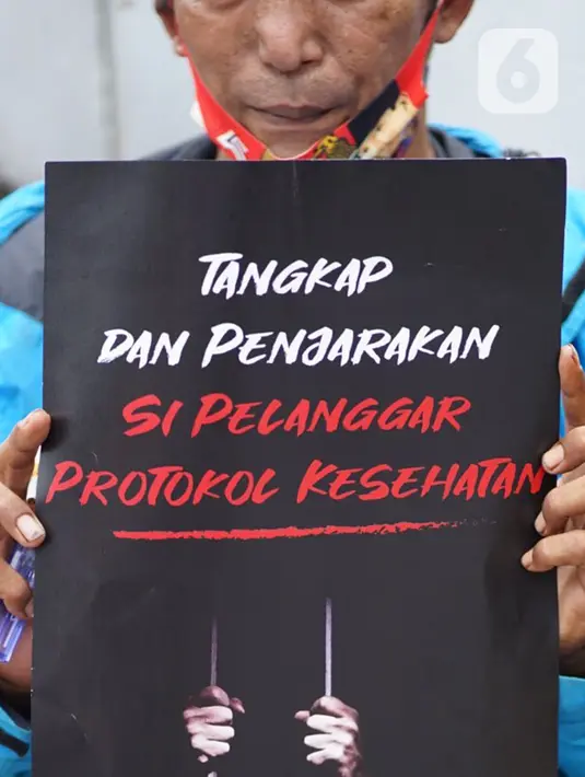 Seorang pengunjuk rasa membawa poster saat menggelar aksi di depan Gedung Polda Metro Jaya, Jakarta, Senin (7/12/2020). Massa menuntut aparat kepolisian segera menangkap Rizieq Shihab atas dugaan pelanggaran protokol kesehatan beberapa waktu lalu. (Liputan6.com/Immanuel Antonius)
