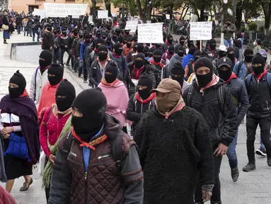 Anggota Tentara Pembebasan Nasional Zapatista (EZLN) berbaris selama protes terhadap kapitalisme dan invasi Rusia di Ukraina, di San Cristobal de las Casas, negara bagian Chiapas, Meksiko (13/3/2022). Zapatista menuntut penghentian perang dan berakhirnya kapitalisme. (AP Photo/Isabel Mateos)
