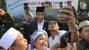 Seorang warga berselfie dengan Presiden Joko Widodo usai melaksanakan salat id Hari Raya Idul Fitri 1 Syawal 1439 H di Lapangan Astrid, Kebun Raya Bogor, Jumat (15/6). (Merdeka.com/Arie Basuki)