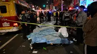 Jenazah para korban, yang diyakini menderita serangan jantung, ditutupi di distrik kehidupan malam populer Itaewon di Seoul, Korea Selatan, Minggu (30/10/2022). Data terbaru yang dirilis pihak berwenang menyebut setidaknya 146 orang telah tewas dan 150 orang lainnya terluka dalam tragedi Halloween Itaewon. (Photo by JUNG YEON-JE / AFP)