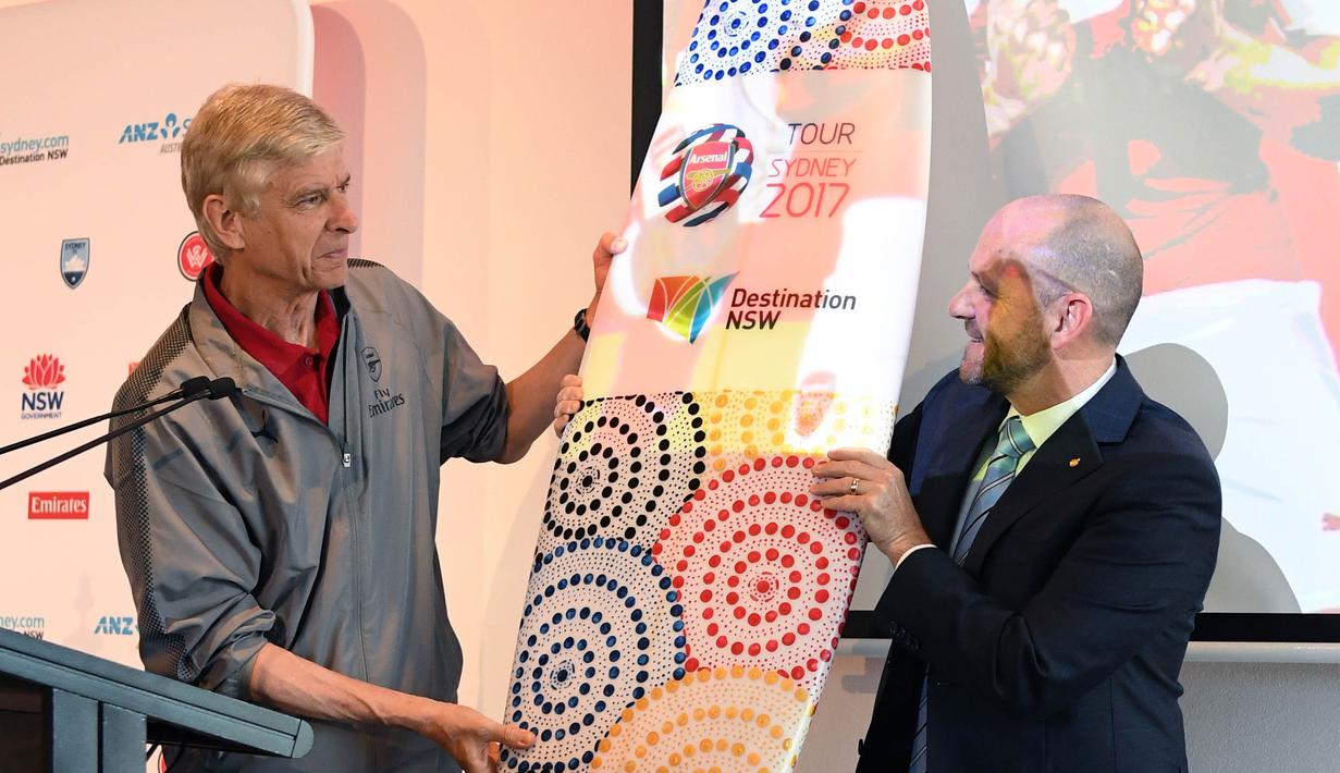 Menteri Pariwisata, Niall Blair, memberi papan surf ke pelatih Arsenal, Arsene Wenger di Museum Seni Kontemporer, Sydney, Selasa (11/7/2017). Arsenal melakukan tur pramusim ke Australia dengan melawan Sydney FC dan Sydney Wanderers. (EPA/David Moir)