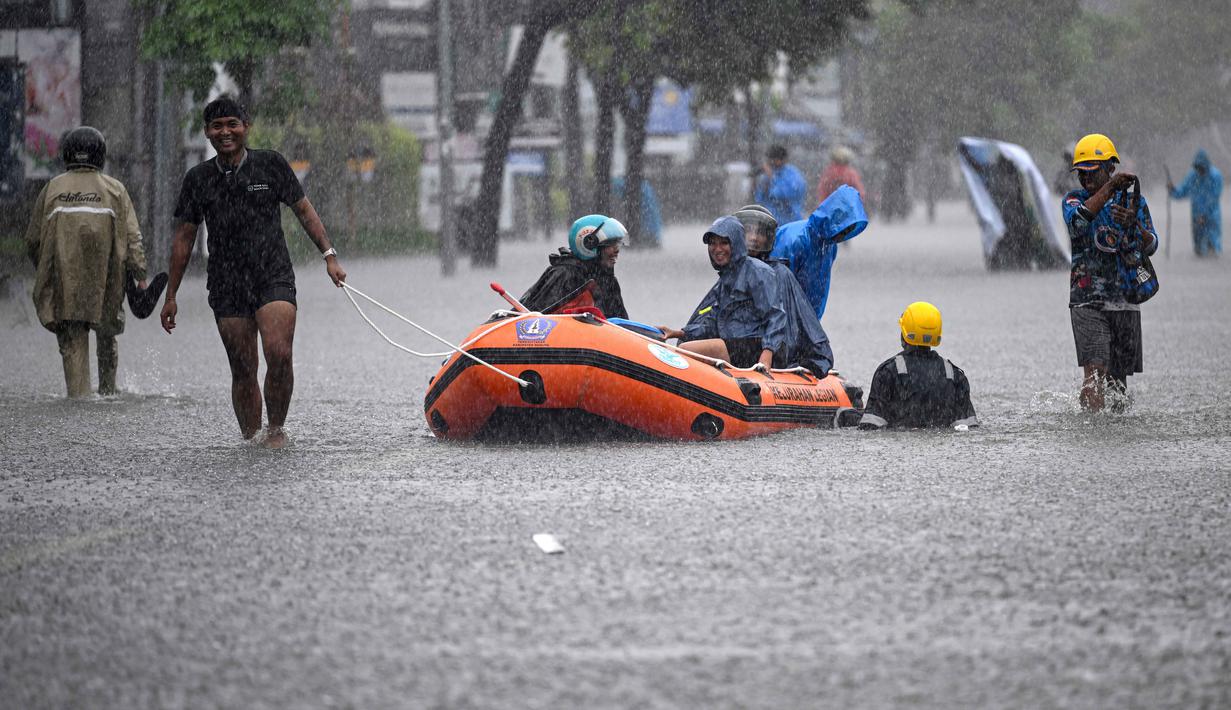 Warga setempat mengangkut tamu hotel menggunakan perahu karet melalui jalan yang tergenang air akibat banjir setelah hujan lebat di Legian Kuta, Denpasar, Bali, pada Selasa 24 Februari 2026. Banjir kembali melanda sejumlah kawasan di pulau Dewata. (SONNY TUMBELAKA/AFP)