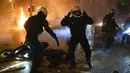 Seorang polisi terluka di jalan ketika rekan-rekannya bereaksi dalam bentrokan di Athena, Yunani, Selasa (9/3/2021). Bentrokan parah terjadi di Athena setelah pemuda yang memprotes insiden kekerasan polisi menyerang kantor polisi dengan bom bensin dan melukai satu petugas. (AP Photo/Aggelos Barai)