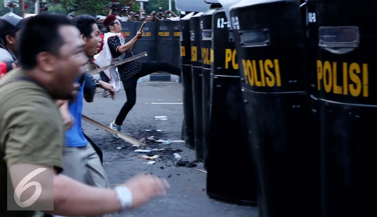 Mahasiswa menyerang polisi yang berjaga saat unjuk rasa di Jalan Medan Merdeka Barat, Jakarta, Kamis (20/10). Mahasiswa menagih janji Nawacita pemerintahan Jokowi-JK. (Liputan6.com/Gempur M Surya)