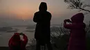 Wisatawan mengambil foto matahari terbit di Desa Hua Zhu, Xiapu, Provinsi Fujian, China, Kamis (12/12/2019). Xiapu menjadi daya tarik tersendiri bagi fotografer pemula karena jauh dari gedung pencakar langit dan hiruk pikuk kota-kota besar di China. (RETAMAL HECTOR/AFP)