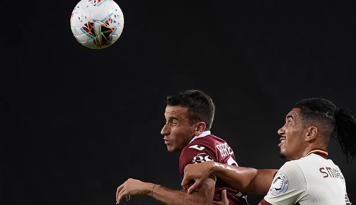 Pemain depan Torino, Alejandro Berenguer berebut bola dengan bek AS Roma, Chris Smalling pada pekan ke-37 Liga Italia di stadion Grande Torino di Turin, Rabu (29/7/2020). AS Roma berhasil mengalahkan tuan rumah Torino 3-2 meski sempat tertinggal lebih dulu. (Fabio Ferrari/LaPresse via AP)