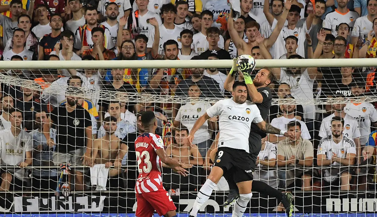 Penjaga gawang Atletico Madrid, Jan Oblak (kanan) melakukan penyelamatan saat ia bersaing dengan pemain depan Valencia, Maxi Gomez selama pertandingan lanjutan La Liga Spanyol di stadion Mestalla di Valencia (30/8/2022). Atletico Madrid menang tipis atas tuan rumah Valencia 1-0. (AFP/Jose Jordan)