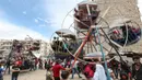 Anak-anak Suriah bermain di taman hiburan sementara ketika merayakan Idul Fitri yang menandai akhir bulan suci Ramadan di kota Idlib, Suriah, Senin (24/5/2020). Anak-anak tersebut menikmati permainan yang mungkin jarang mereka rasakan di tengah peperangan yang masih berkecamuk. (OMAR HAJ KADOUR/AFP)
