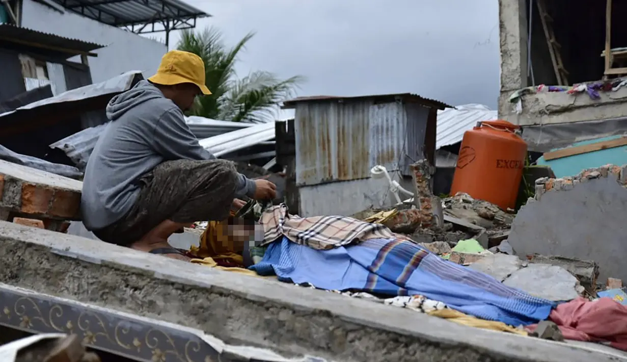 Seorang pria berduka atas jenazah korban gempa di Kota Mamuju, Sulawesi Barat, Indonesia, Jumat (15/1/2021). BMKG menyebut pusat gempa berada di darat, 6 kilometer timur laut Majene pada kedalaman 10 kilometer. (Firdaus/AFP)