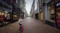 Seorang perempuan berjalan di sepanjang jalan yang kosong di Amsterdam sehari setelah Perdana Menteri Belanda mengumumkan lockdown ketat, Selasa (15/12/2020). Pemerintah Belanda menetapkan lockdown total untuk meredam COVID-19 dimulai pada periode Natal. (ROBIN VAN LONKHUIJSEN/AN /AFP)