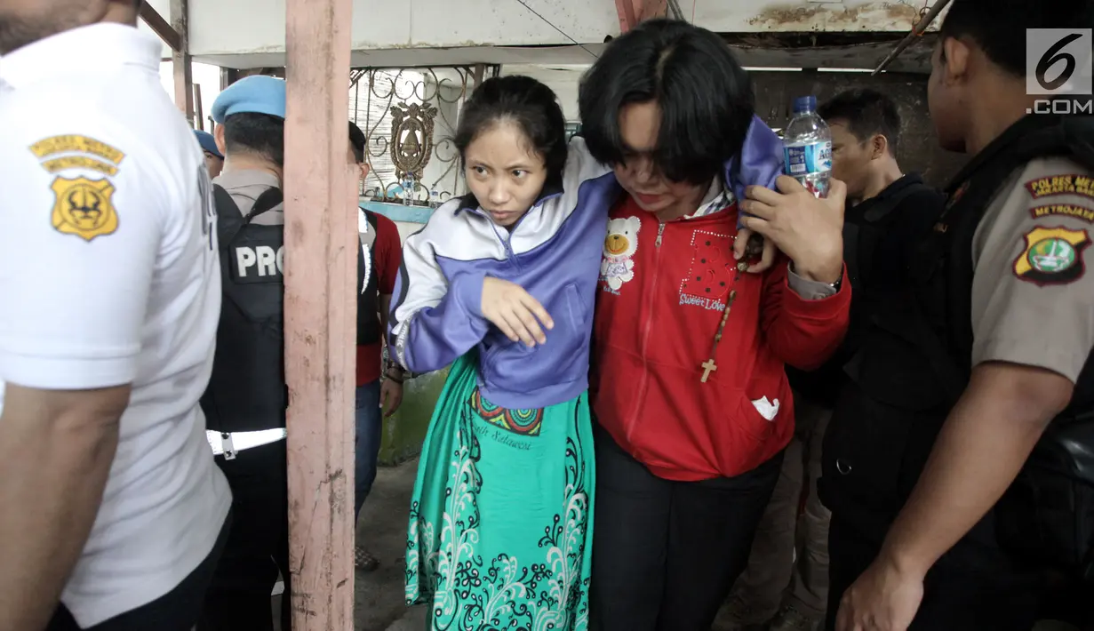 Polisi wanita (polwan) menuntun seorang tersangka wanita usai menggerebek peredaran narkoba di kawasan Kampung Ambon, Cengkareng, Jakarta Barat, Rabu (24/1). Petugas juga masih bersiaga di sekitar lokasi. (Liputan6.com/Arya Manggala)