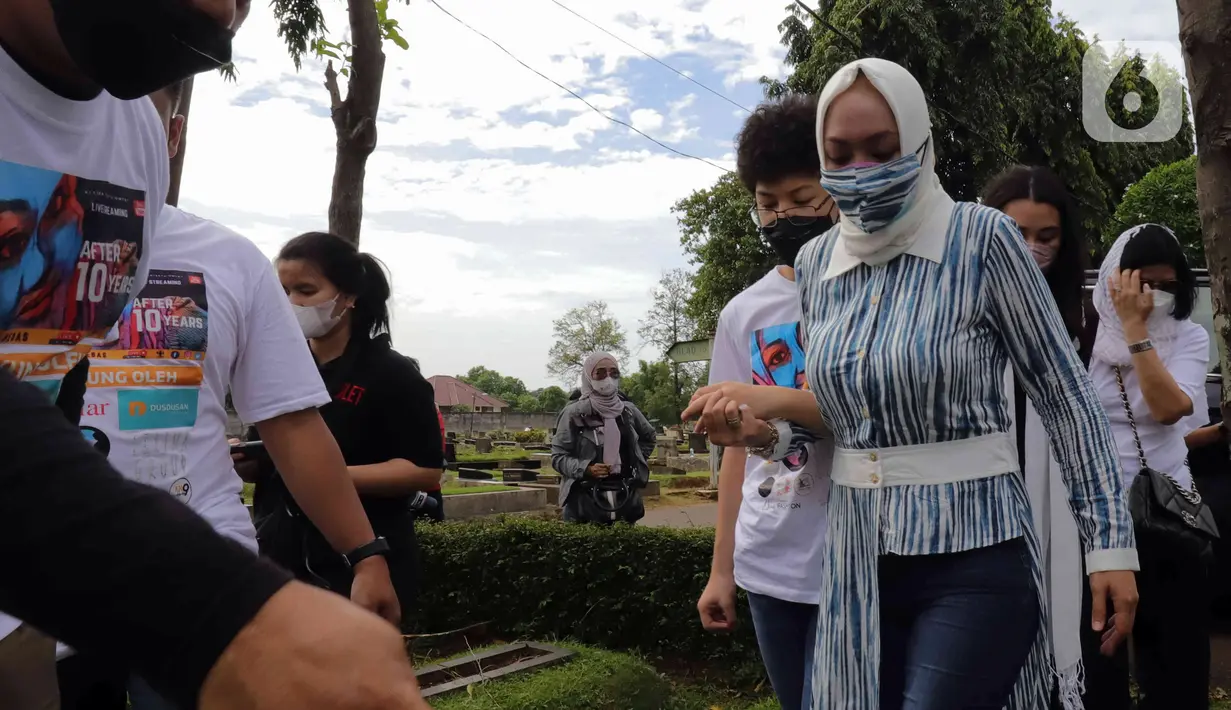 Mantan Anggota DPR Angelina Sondakh bersama kedua anaknya Aaliyah Massaid dan Keanu Jabbar Massaid saat ziarah makam di TPU Jeruk Purut, Jakarta Selatan, Kamis (3/3/2022). Kedatangan mereka untuk berziarah ke makam Adjie Massaid dan bapak dari Adjie Massaid. (Liputan6.com/Herman Zakharia)