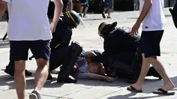 Polisi memeriksa kondisi seorang pria yang menjadi korban bentrok di kota Marseille, Prancis (11/6/2016). Bentrok terjadi menjelang pertandingan sepak bola Euro 2016 antara Inggris dan Rusia. (AFP Photo/ Tobias Schwarz)