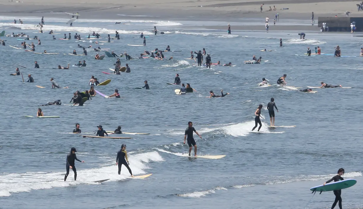 Peselancar menunggu ombak dari pantai Katase-kaigan di Fujisawa, prefektur Kanagawa, dekat Tokyo, Senin (8/6/2020). Jepang mengangkat keadaan darurat coronavirus-nya, mengakhiri pembatasan secara nasional ketika bisnis mulai dibuka kembali. (AP Photo/Koji Sasahara)
