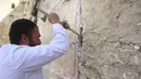 Pekerja Tembok Barat menQghapus pesan dan doa, yang ditulis di selembar kertas oleh ribuan orang yang "ditujukan kepada Tuhan", dari celah-celah situs suci Yahudi di Kota Tua Yerusalem (30/3/2022). Pembersihan sebagai persiapan untuk liburan Paskah Yahudi yang akan datang. (AFP/Hazem Bader)