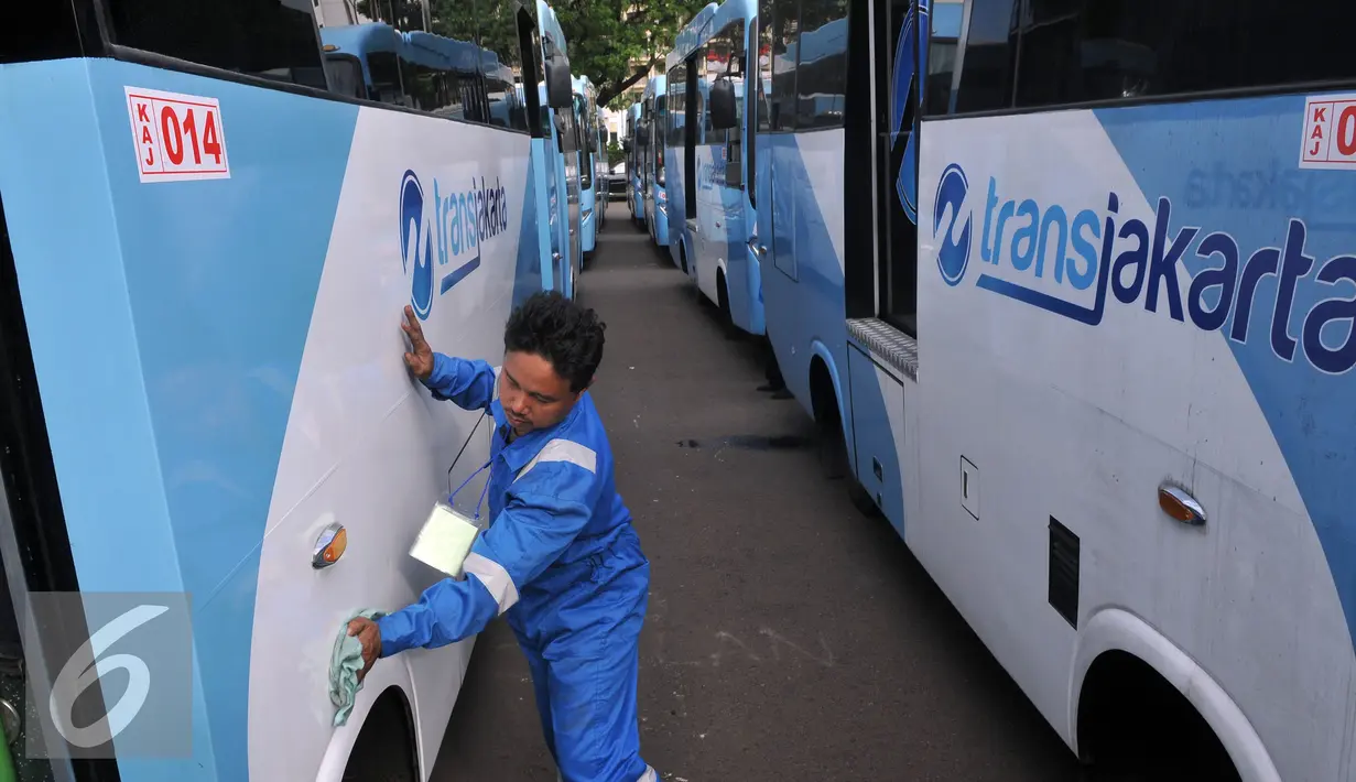 Petugas membersihkan Kopaja terintegrasi Transjakarta terparkir di Parkir Timur Senayan, Jakarta, Selasa (22/12). Saat ini terdapat 320 bus tampilan baru Kopaja AC yang akan beroperasi di rute-rute yang terintegrasi.  (Liputan6.com/Johan Tallo)