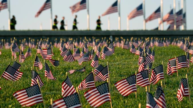 Aktivis dari COVID Memorial Project meletakkan ribuan bendera Amerika berukuran kecil di di halaman National Mall di Washington, Selasa (22/9/2020). Ribuan bendera itu menandai 200 ribu nyawa yang hilang akibat virus corona Covid-19 di Amerika Serikat. (AP Photo/J. Scott Applewhite)