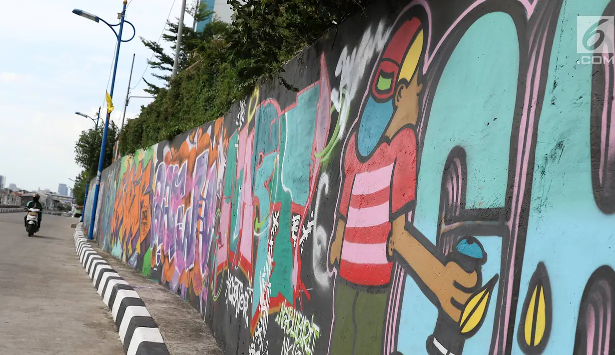 Pengendara melintasi jalur inspeksi Sungai Ciliwung di Jakarta, Kamis (27/12). Mural yang dibuat oleh beberapa komunitas tersebut menjadikan jalur inspeksi Sungai Ciliwung tampak lebih berwarna dan asri. (Liputan6.com/Immanuel Antonius)