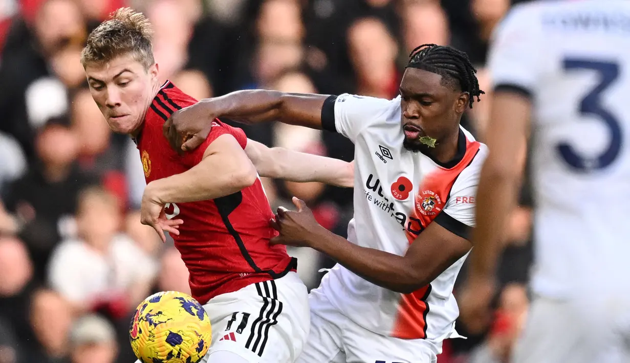 Pemain Manchester United, Rasmus Hojlund (kiri) berebut bola dengan pemain Luton Town, Teden Mengi saat laga lanjutan Liga Inggris 2023/2024 di Old Trafford, Manchester, Inggris, 11 November 2023. (AFP/Oli Scarff)
