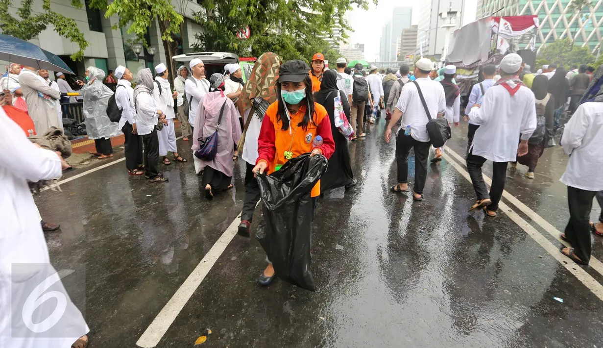 Seorang petugas kebersihan DKI Jakarta membawa kantung plastik untuk membersihkan sampah  usai aksi damai 2 Desember di kawasan Jalan MH Thamrin, Jakarta, Jumat (2/12). (Liputan6.com/Ferbian Pradolo)