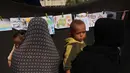 Dalam coretannya, mereka mengungkap penderitaan, kengerian, dan harapan mereka akan terjadinya perdamaian. Tampak dalam foto, orang-orang yang membawa anak-anak melihat pameran di sebuah sekolah yang diubah menjadi tempat penampungan bagi pengungsi Palestina di kawasan Al-Rimal, Kota Gaza, pada 5 November 2025. (Omar AL-QATTAA/AFP)