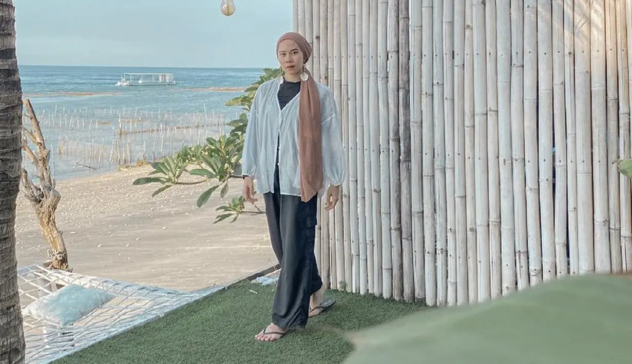 Blouse putih dengan pants loose pants terkesan santai dipilih Ajeng ketika berlibur.  (Dok. Instagram @ajeng.dinanti)