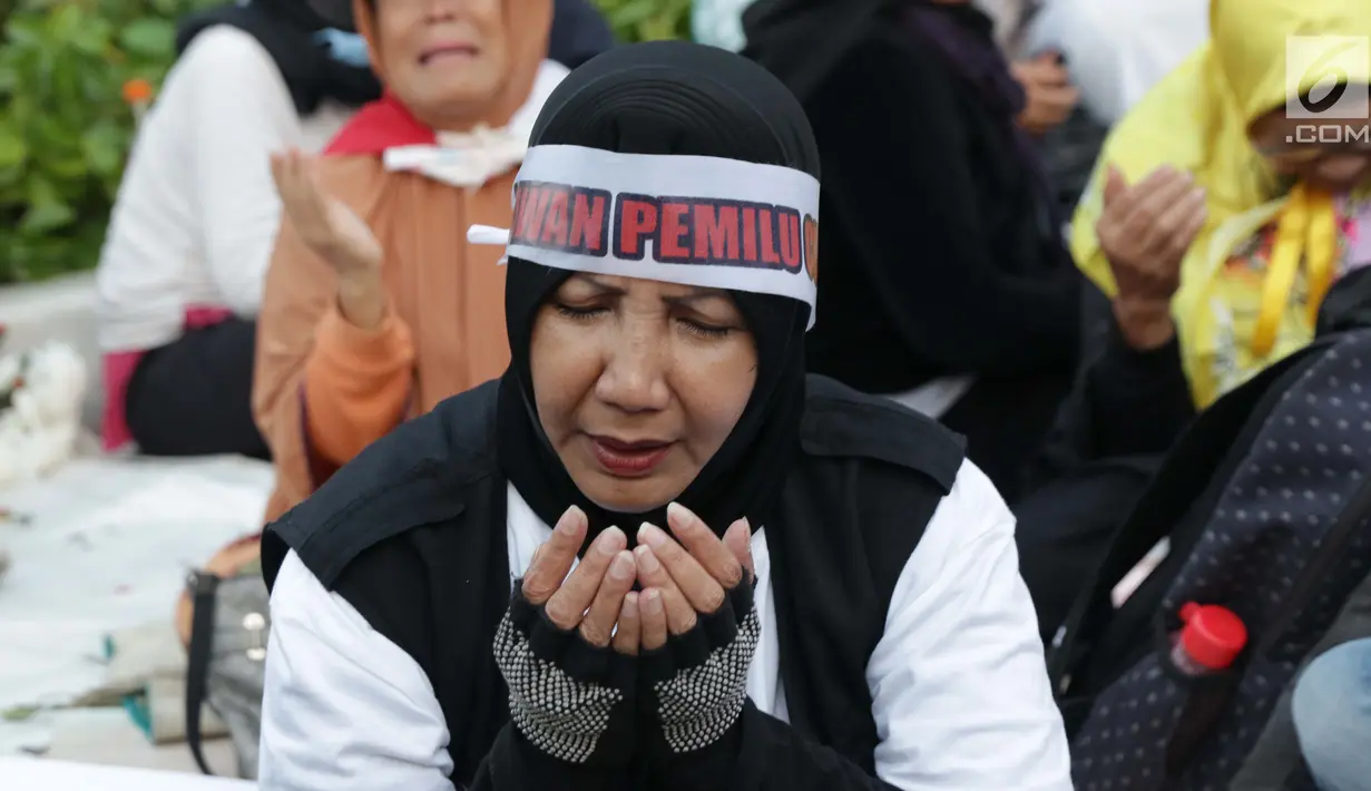 Peserta aksi massa Gerakan Nasional Kedaulatan Rakyat berdoa bersama saat unjuk rasa di depan Gedung Bawaslu, Jalan MH Thamrin, Jakarta, Selasa (21/5/2019). Dalam aksinya, mereka Bawaslu memeriksa hasil Pemilu 2019 yang dinilai banyak terdapat kecurangan. (Liputan6.com/Helmi Fithriansyah)