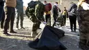 Polisi Irak memasukkan jasad korban kesadisan kelompok ISIS ke kantong jenazah, di sebuah kuburan massal yang ditemukan di Kota Ramadi, sebelah barat Baghdad, Selasa (26/1). Kuburan massal tersebut berisi sisa-sisa sekitar 40 jasad (AFP/ MOADH AL-DULAIMI)