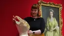 Pameran ini akan digelar di The King's Gallery, Istana Buckingham, London, Inggris, mulai dari 10 April hingga musim gugur 2026. Tampak dalam foto, seorang anggota staf Royal Collection Trust menyesuaikan gaun malam dari tahun 1952 yang dikenakan oleh Ratu Elizabeth II, yang dipamerkan di pameran 'Queen Elizabeth II: Her Life in Style', di The King's Gallery, Istana Buckingham, London, Inggris, Kamis 9 April 2026. (AP Photo/Kirsty Wigglesworth)