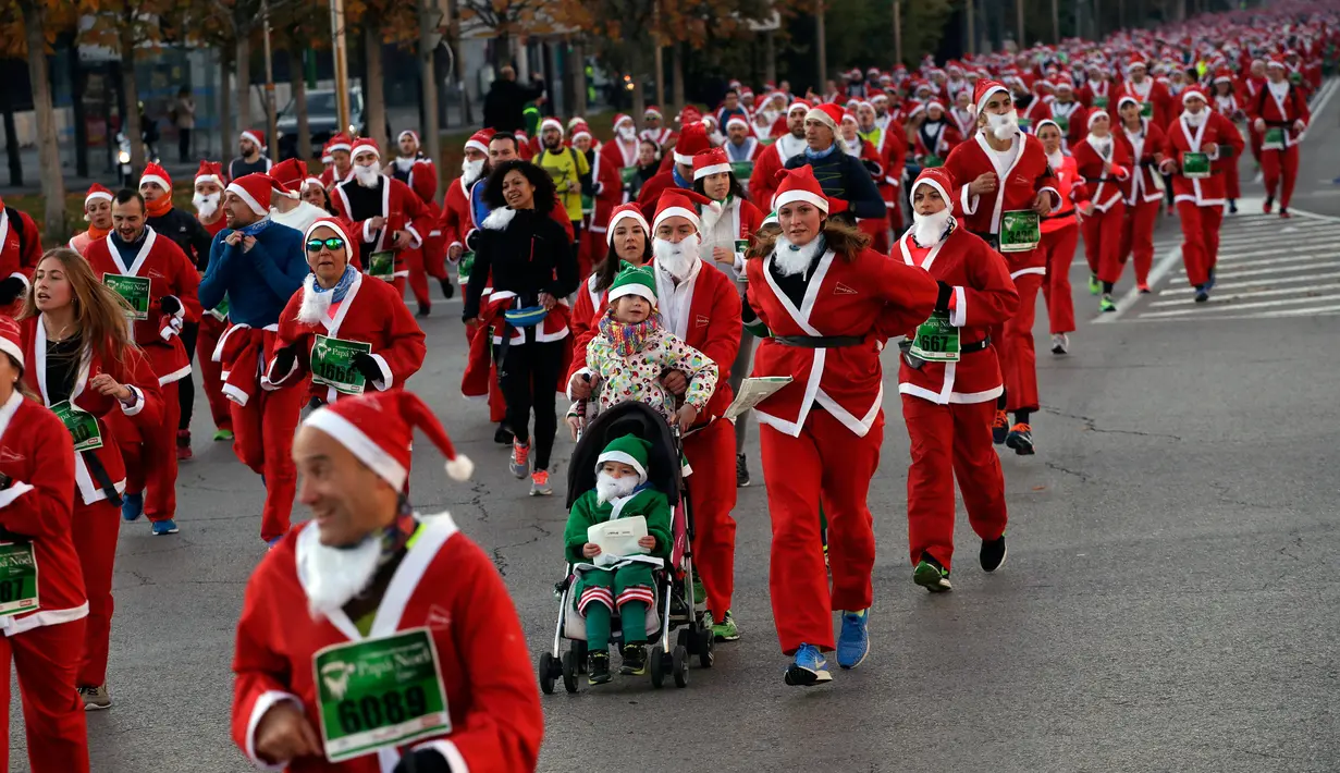 Orang-orang mengenakan kostum Sinterklas mengambil bagian dalam Santa Claus Run di Madrid, Spanyol, Minggu (9/12). Ribuan memeriahkan acara yang sudah diselenggarakan sejak 7 tahun yang lalu. (AP/Emilio Morenatti)