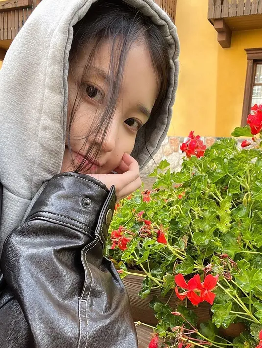 IU yang sama cantiknya dengan bunga yang mekar di belakangnya.  [Foto: Instagram/ dlwlrma]