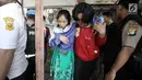 Polisi wanita (polwan) menuntun seorang tersangka wanita usai menggerebek peredaran narkoba di kawasan Kampung Ambon, Cengkareng, Jakarta Barat, Rabu (24/1). Petugas juga masih bersiaga di sekitar lokasi. (Liputan6.com/Arya Manggala)
