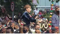 Momen Jokowi berdiri menyapa para warga dan bagikan kaos saat prosesi Kirab pernikahan Kaesang-Erina. (Dok. Istimewa)